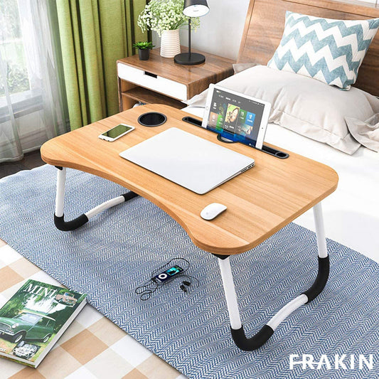 This foldable laptop table features a smooth wooden top with a built-in cup holder and a slot for holding tablets or phones.