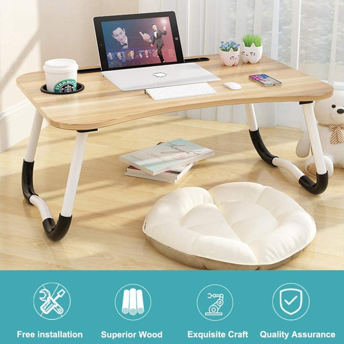 This foldable laptop table features a smooth wooden top with a built-in cup holder and a slot for holding tablets or phones.